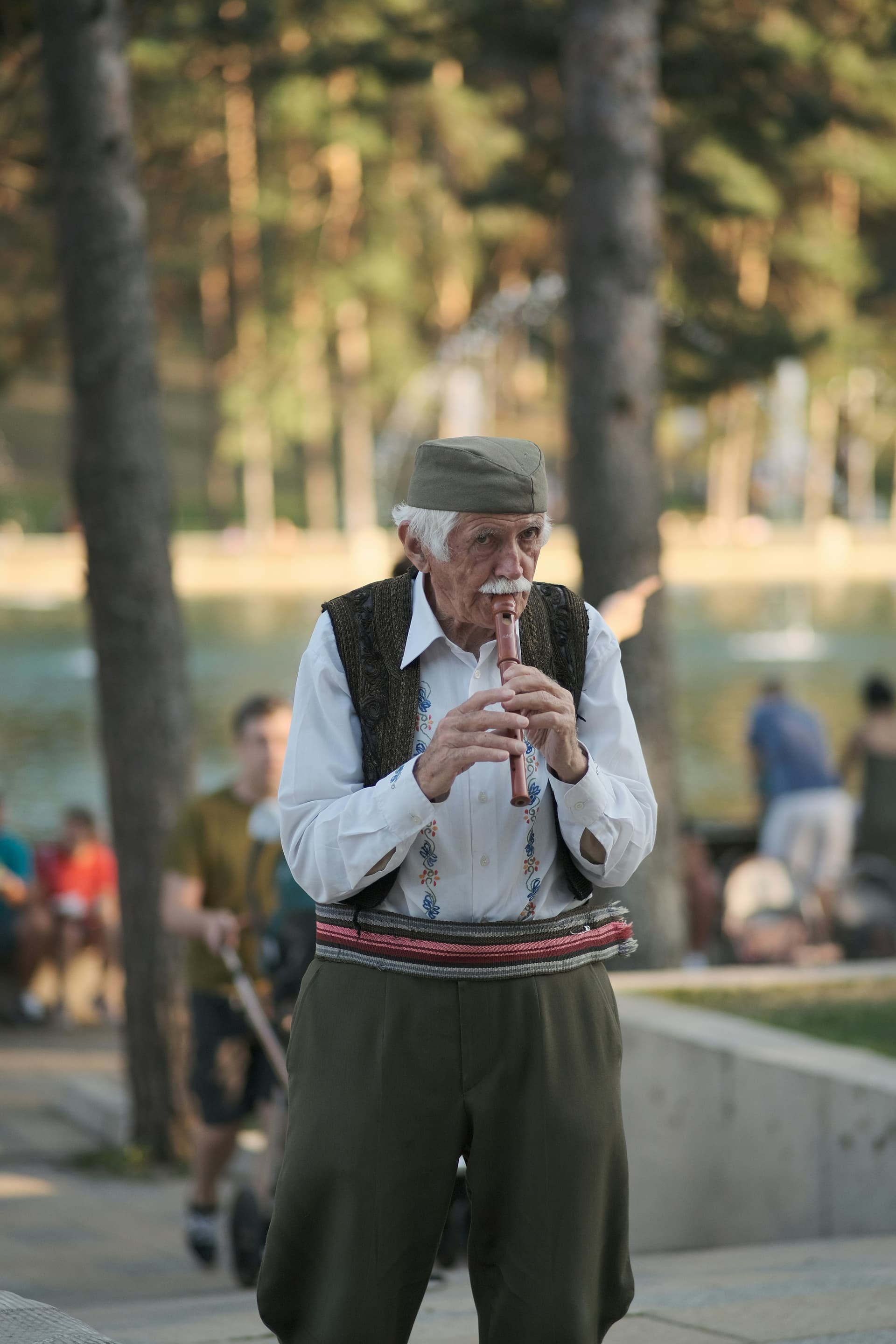 Stariji covek svira frulu ispred Zlatiborskog jezera